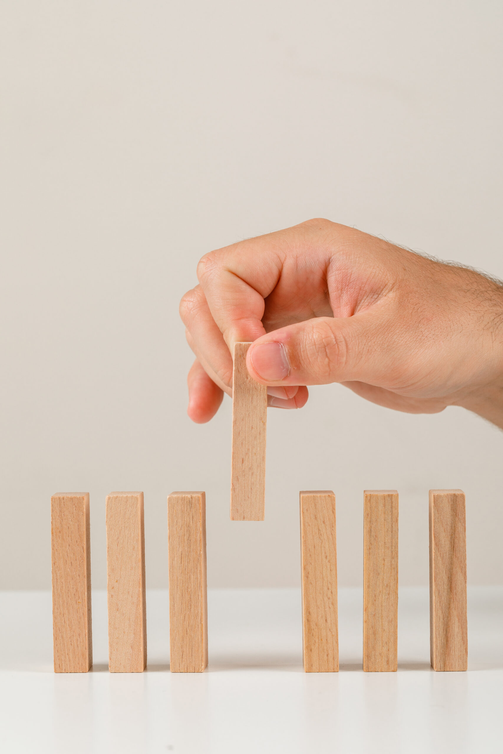Main plaçant un bloc en bois parmi d’autres, représentant la prise de décision stratégique et le management en freelance.