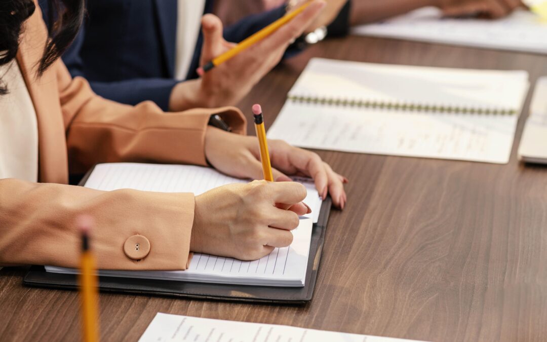 Équipe en réunion professionnelle analysant des documents et prenant des notes lors d’une séance de travail.